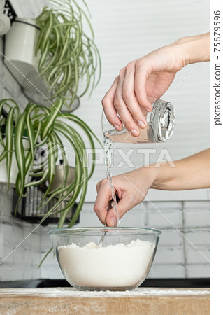 eggs, flour and water. Making dough by female hands in white moden kitchen. Eggs 75879596