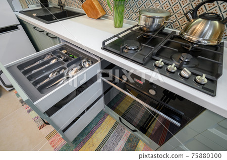 Drawers pulled out in cabinet at luxury teal and white modern kitchen furniture 75880100
