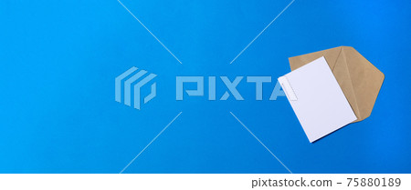 brown envelope with a blank white card on blue background. Flat lay, top view. brown envelope with a blank white card on blue background. Flat lay, top view. 75880189
