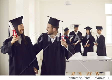 Young happy couple classmates asian girl and caucasian boy celebrating getting diploma Young happy couple classmates asian girl and caucasian boy celebrating getting diploma 75880507