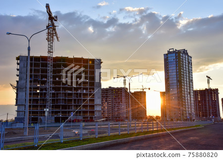 View on the large construction site with tower cranes and buildings on sunset background. View on the large construction site with tower cranes and buildings on sunset background. 75880820