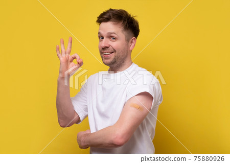 Caucasian man showing his vaccinated arm. He received a corona vaccine looking at camera. Caucasian man showing his vaccinated arm. He received a corona vaccine looking at camera. 75880926