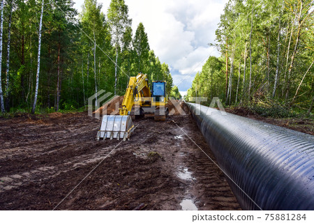 Excavator during earthwork for laying Crude oil and Natural gas pipeline in forest area.   75881284