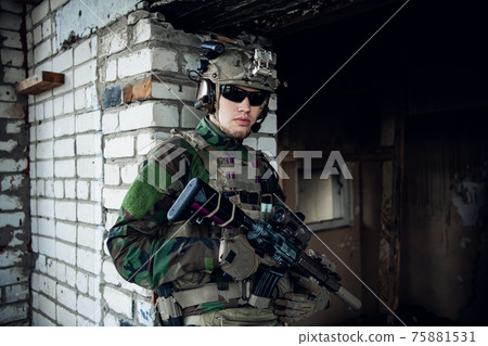 Military man with assault rifle standing inside building, he is ready for combat 75881531