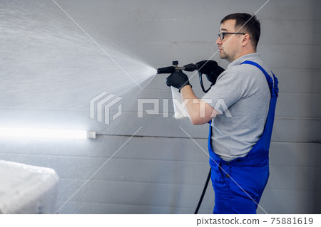 Car washing and detailing. Professional worker is washing a black car by pressure washer at a car wash. Car washing and detailing. Professional worker is washing a black car by pressure washer at a car wash. 75881619