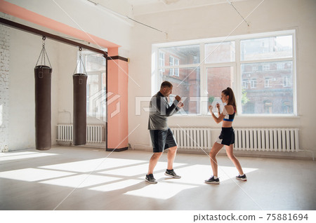 Woman training boxing with personal trainer. Instructor teaching female boxer fighting practice together 75881694