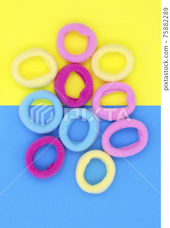 Multicolored little rubber bands for hair, on blue yellow paper background 75882289