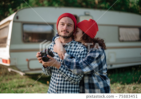 Romantic couple with a camera in nature near the trailer at home. Romantic couple with a camera in nature near the trailer at home. 75883451