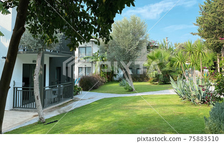 The territory of the hotel in the resort town with an incredibly beautiful garden, beautiful flowering shrubs and fruit trees. The building on the territory of the hotel, the concept of recreation The territory of the hotel in the resort town with an incredibly beautiful garden, beautiful flowering shrubs and fruit trees. The building on the territory of the hotel, the concept of recreation 75883510