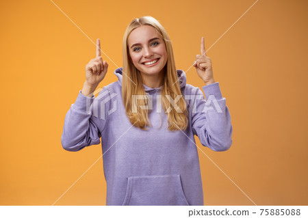 Helpful friendly-looking supportive charming female friend pointing up showing awesome new product advertisement suggesting check out tilting head gladly smiling help out, orange background Helpful friendly-looking supportive charming female friend pointing up showing awesome new product advertisement suggesting check out tilting head gladly smiling help out, orange background 75885088