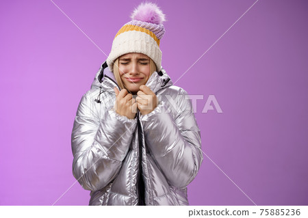 Unhappy sobbing whining cute blond girl pull jacket tight body close eyes crying freezing cold standing snowy winter resort shaking low temparature, purple background suffering discomfort 75885236