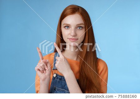 Assertive good-looking redhead girl know what talking about pointing upper left corner index fingers showing confidently good product recommend check out standing blue background 75888160