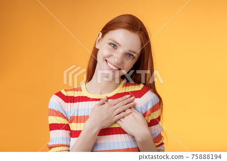 Pleased tender feminine good-looking redhead woman receive compliment confession touch heart feel warmth dearest moment smiling delighted lovely keep love inside soul, standing orange background 75888194