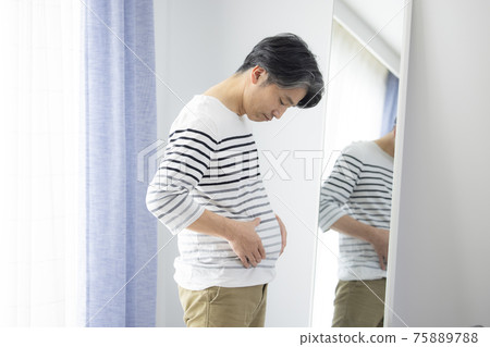 Middle-aged man who cares about proportions in front of the mirror 75889788