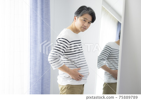 Middle-aged man who cares about proportions in front of the mirror 75889789