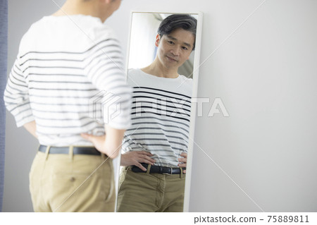 Middle-aged man who cares about proportions in front of the mirror 75889811