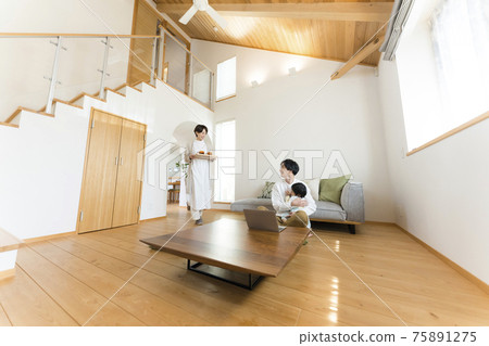 Father teleworking while babysitting in the living room 75891275