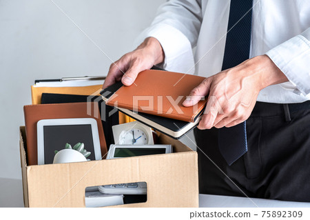 Images of businessman carrying packing up all his personal belongings and files into a brown cardboard box has frustrated and stressed to resignation and signing cancellation contract letter 75892309