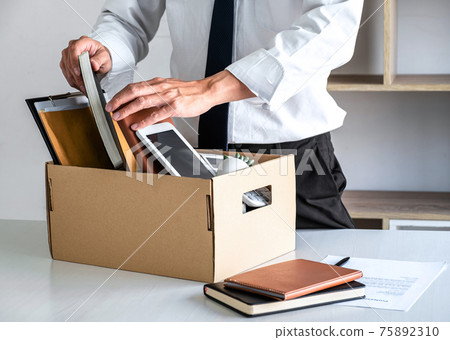 Images of businessman carrying packing up all his personal belongings and files into a brown cardboard box has frustrated and stressed to resignation and signing cancellation contract letter 75892310