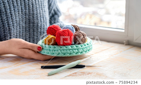 Woman holding knitted couch with yarn balls Woman holding knitted couch with yarn balls 75894234
