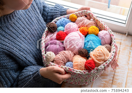 Woman holding knitted couch with yarn balls 75894243