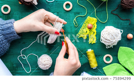 Woman is knitting using hooks and white yarn Woman is knitting using hooks and white yarn 75894299
