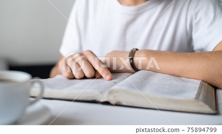 A boy reading a book on the table 75894799