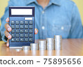A businessman with a calculator and a stack of coins in foreground. Business, finance and growth 75895656
