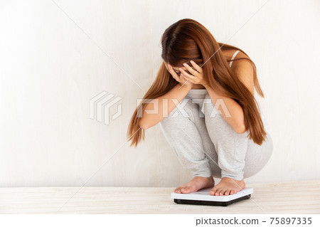 Woman measuring weight Woman measuring weight 75897335