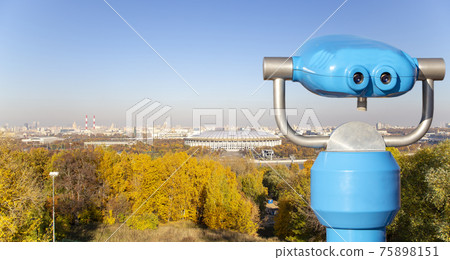 Touristic telescope viewer (binoculars) and view of central Moscow from Sparrow Hills or Vorobyovy Gory observation (viewing) platform-- is on a steep bank 85 m above the Moskva river, or 200 m above 75898151