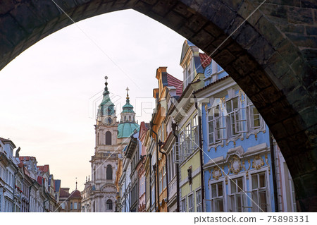 Mala Strana district in Prague, Czhech Republic. A view of the Mostecka street with the Church of Saint Nicolas in the background from under the end of the Charles Bridge 75898331
