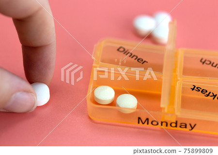 Pill box reminder, hand taking medicine daily pills in colorful box on pink background, elderly,senior,business,health,medication concept modern design 75899809