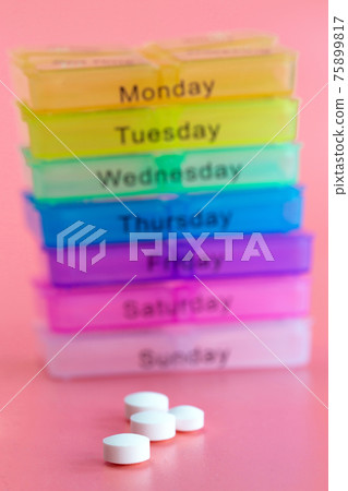 Pill box reminder, hand taking medicine daily pills in colorful box on pink background, elderly,senior,business,health,medication concept modern design 75899817