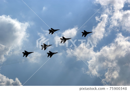 Flight of modern combat fighters on the sky background 75900348