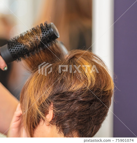 Woman doing her hair with a comb in a beauty salon 75901074