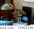 Interior photo with stained glass desk lamp and flower arrangement of Christmas rose 75901596