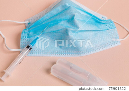On the table is a medical mask with a syringe and medicine for coronavirus. 75901822