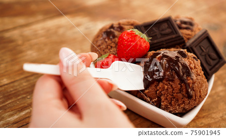 Hand with a spoon. Homemade chocolate ice cream with chocolate and strawberries 75901945