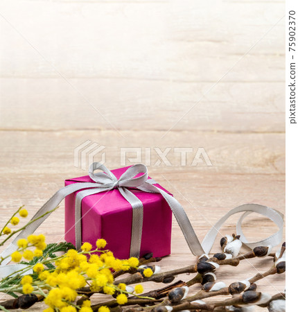Yellow mimosa and fluffy willow. Gift on a wooden background. 75902370