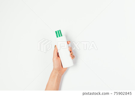 Female hand holding blank bottle of cosmetic product lotion with green cap Female hand holding blank bottle of cosmetic product lotion with green cap 75902845