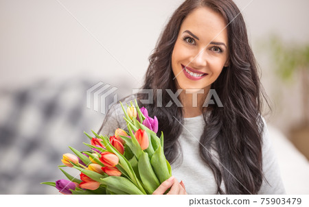 Beautiful dark haired woman holding in hands a lovely bouquet full of tulips during national womens day 75903479