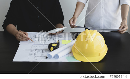 Meeting of engineers and architects in building planning, Consulting and brainstorming experts in architectural planning using blueprints, tape measure, rulers, laptop in designing buildings. Meeting of engineers and architects in building planning, Consulting and brainstorming experts in architectural planning using blueprints, tape measure, rulers, laptop in designing buildings. 75904544