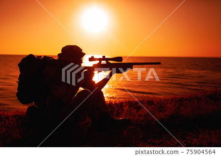 Commando sniper aiming, shooting rifle on seacoast Commando sniper aiming, shooting rifle on seacoast 75904564
