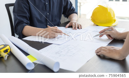 Meeting of engineers and architects in building planning, Consulting and brainstorming experts in architectural planning using blueprints, tape measure, rulers, laptop in designing buildings. Meeting of engineers and architects in building planning, Consulting and brainstorming experts in architectural planning using blueprints, tape measure, rulers, laptop in designing buildings. 75904565