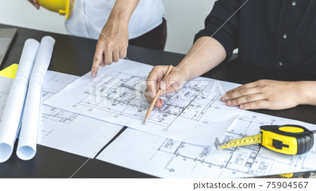 Meeting of engineers and architects in building planning, Consulting and brainstorming experts in architectural planning using blueprints, tape measure, rulers, laptop in designing buildings. 75904567