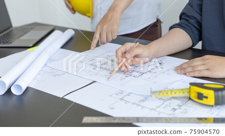 Meeting of engineers and architects in building planning, Consulting and brainstorming experts in architectural planning using blueprints, tape measure, rulers, laptop in designing buildings. Meeting of engineers and architects in building planning, Consulting and brainstorming experts in architectural planning using blueprints, tape measure, rulers, laptop in designing buildings. 75904570