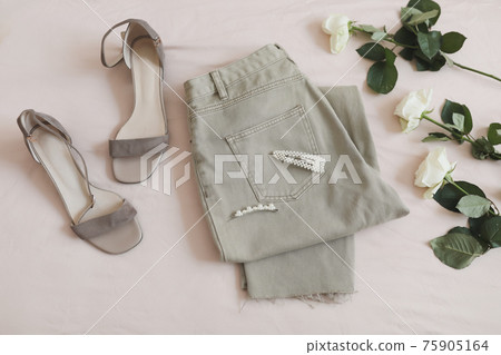 Overhead view of woman's casual spring summer outfit. Jeans, sandals and bouquet of flowers on beige background. Flat lay, top view. Overhead view of woman's casual spring summer outfit. Jeans, sandals and bouquet of flowers on beige background. Flat lay, top view. 75905164
