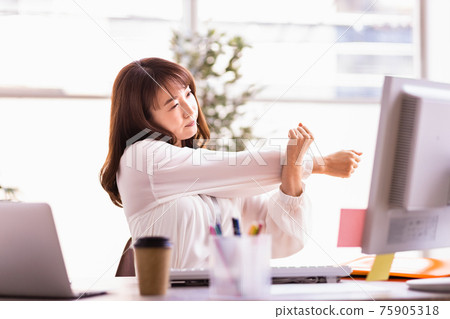 Woman stretching during desk work Woman stretching during desk work 75905318