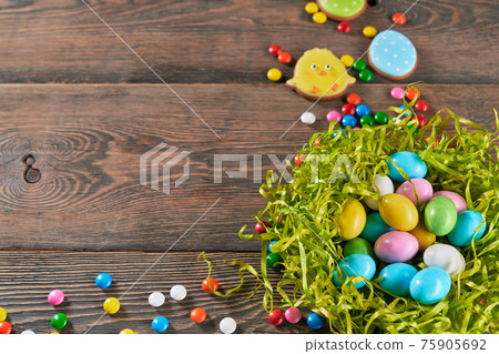 Decorative nest filled with easter eggs on wooden background 75905692