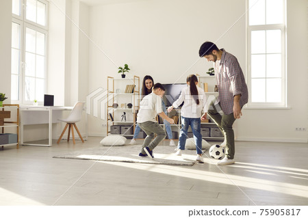 Happy family staying at home have fun together play football in living-room Happy family staying at home have fun together play football in living-room 75905817
